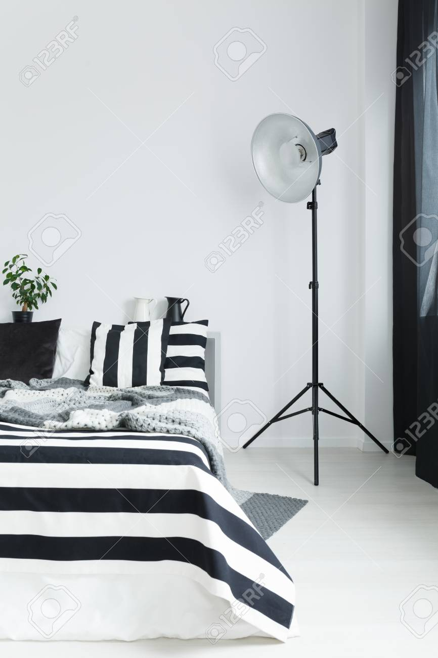 Bed With Striped Black And White Bedding And Floor Lamp intended for size 866 X 1300